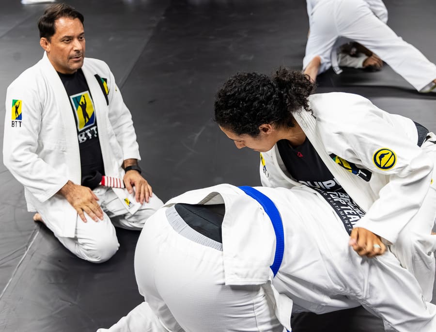 A coach guiding a new adult student through a position on the mats at BTT Bridgewater