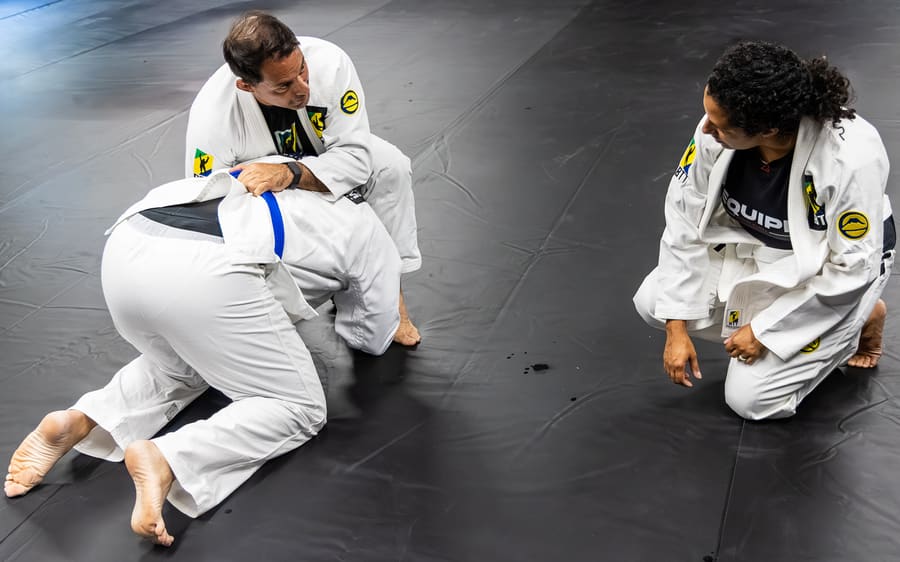 Two adults rolling on the mats while a coach watches at BTT Bridgewater