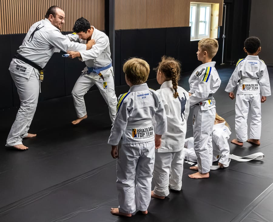 Young students in gis lined up watching two coaches demonstrate in kids class at BTT Bridgewater